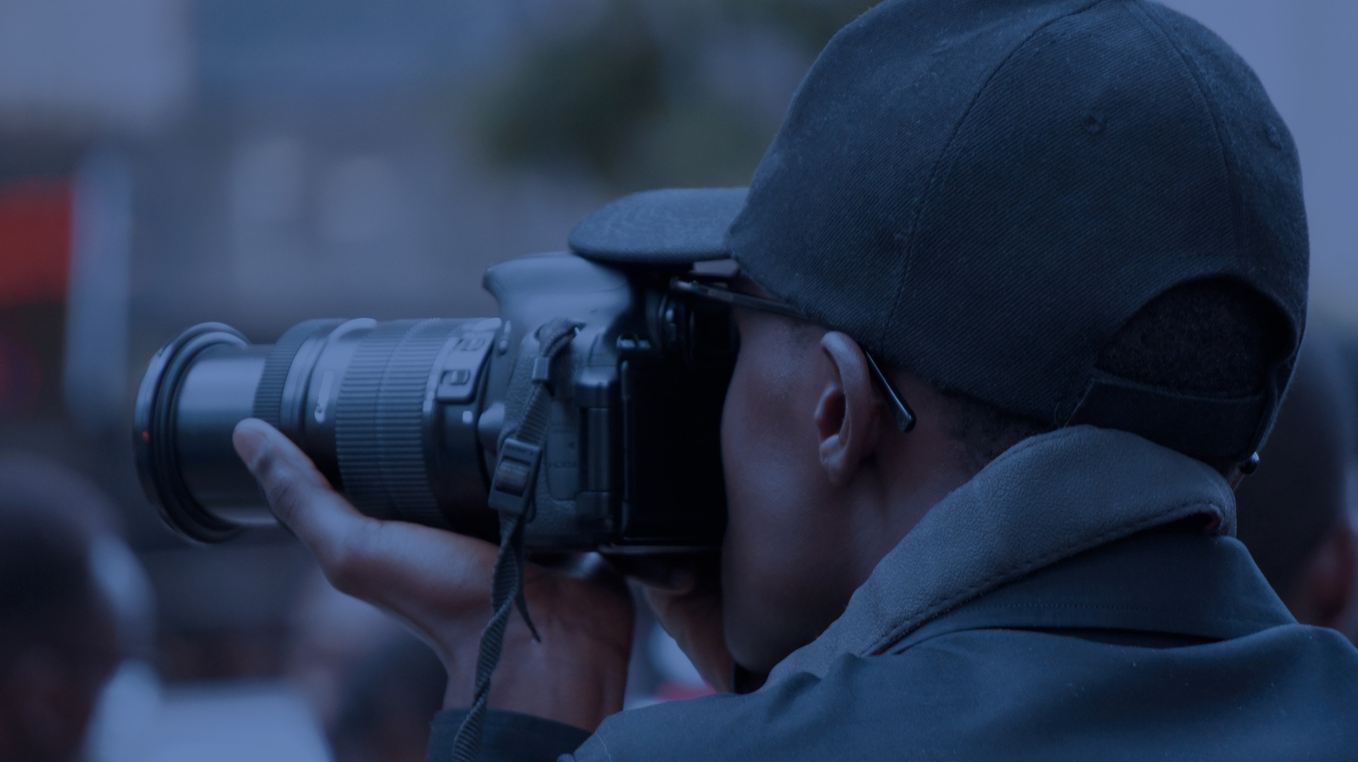 close-up image of a photographer holding a camera with a zoom lens